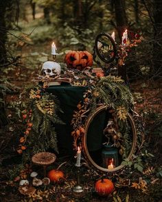 a table topped with pumpkins and candles in the woods