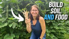 a woman holding up a stalk of plant with the words build soil and food on it