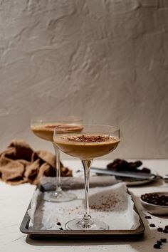 two glasses filled with liquid sitting on top of a tray next to some chocolate chips