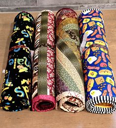 four rolls of colorful fabric on a wooden surface