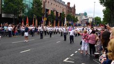 a group of people that are standing in the street with flags and marching gear on