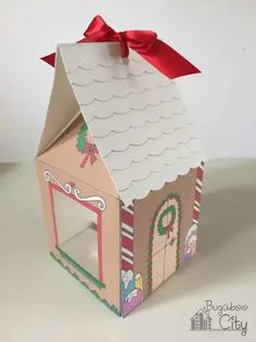 a small cardboard house with a red bow on it's roof and windows is shown