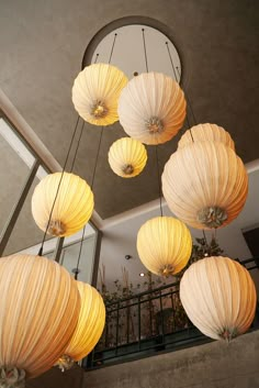 several white paper lanterns hanging from the ceiling in a room with stairs and railings