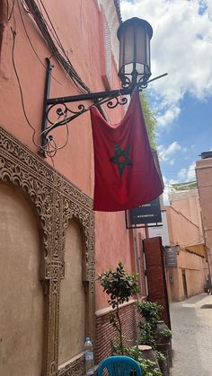 a blue chair sitting on the side of a building next to a red flag hanging from a light pole