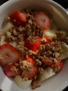 a white bowl filled with granola and strawberries