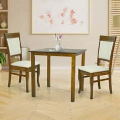 a dining table with two chairs and a vase on it in front of a painting