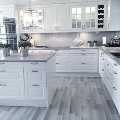 a kitchen with white cabinets and wood floors