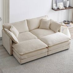 a large white couch sitting on top of a wooden floor next to a table and chair