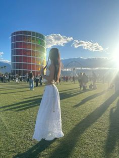 a woman in a white dress standing on top of a field