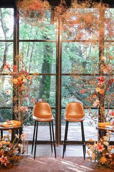 two chairs sitting next to each other in front of large windows with flowers on them