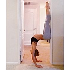 a woman is doing a handstand on the floor in front of a door