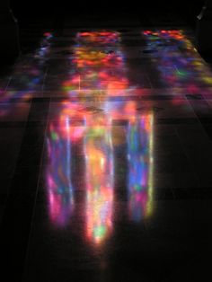 the floor is covered in colorful lights and shadows, with one person standing on it