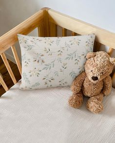 a brown teddy bear sitting on top of a bed next to a pillow