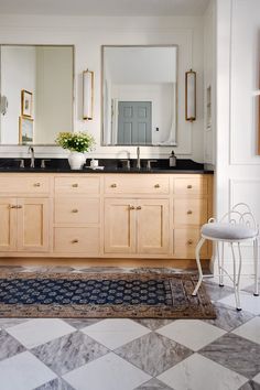 a bathroom with two sinks, mirrors and a rug on the floor in front of it