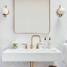 a bathroom sink with a mirror above it and gold faucets on the wall