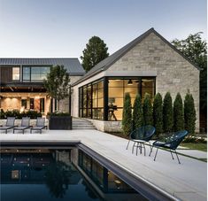 a house with a swimming pool and lounge chairs in front of the house at dusk