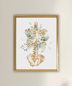 a white wall with a gold framed art piece hanging on the wall next to a plant