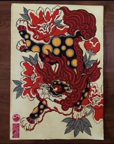 a painting on a piece of paper with flowers and a dragon in the middle, sitting on a wooden surface