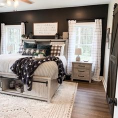 a bedroom with black walls and white bedding in the center is decorated with plaid throw pillows