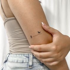 a woman's arm with a small bird tattoo on the left side of her arm