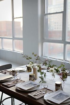 the table is set with place settings and flowers in vases on each side, along with silverware