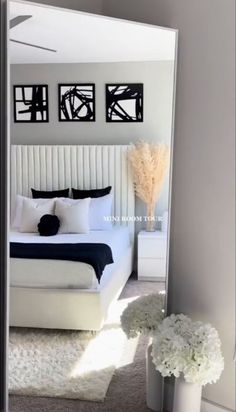 a bedroom with a large mirror on the wall and flowers in vases next to it