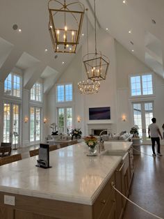 a large open concept living room with high ceilings and chandeliers hanging from the ceiling