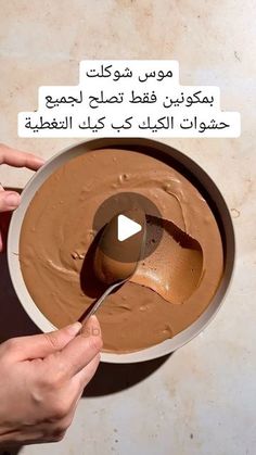 two hands are holding a bowl with chocolate in it and one hand is spooning something into the bowl