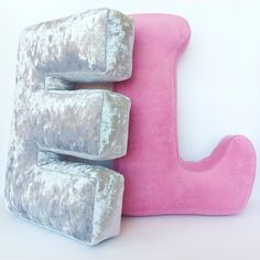 the letter j is made out of pink and grey velvet material, with two pillows attached to it