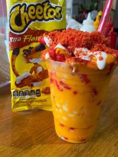 a yellow drink with red and white toppings in a cup next to a bag of cheetos