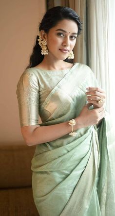 a woman in a green sari standing next to a window with her hands on her hips