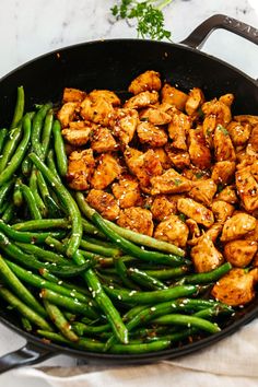 chicken, green beans and sesame seeds in a skillet on a marble countertop