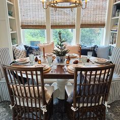 a dining room table set for four with chairs around it and a christmas tree in the center