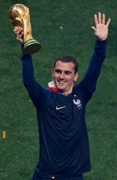 the soccer player is holding his trophy up in victory with both hands and smiling at the camera