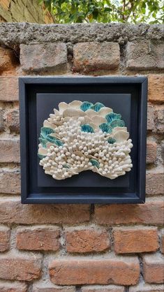 a blue and white wall hanging on the side of a brick building with shells in it