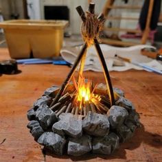 a fire pit made out of sticks and rocks on top of a wooden table next to a potted plant