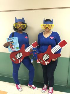 two women in costumes are holding guitars and wearing cat - ears on their heads while standing next to each other