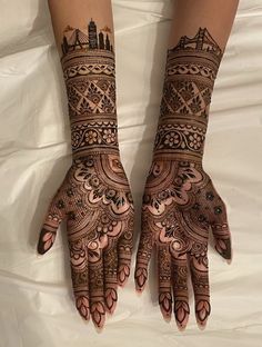 two hands with henna designs on them, one is showing off the intricate design