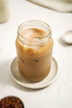 a glass jar filled with liquid sitting on top of a plate next to a spoon