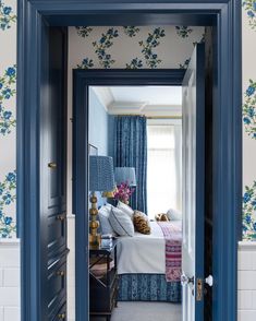 an open door leading to a bedroom with blue walls and floral wallpaper on the walls