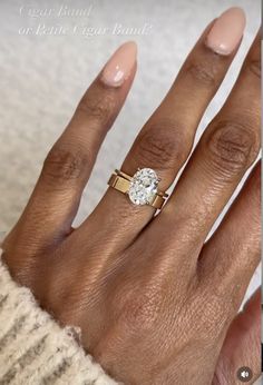 a woman's hand wearing a gold ring with a white diamond on it and the middle finger