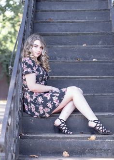 a woman sitting on some stairs with her legs crossed