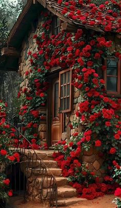 a house with red flowers growing on the side and steps leading up to it's door