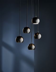 four black and white lights hanging from a ceiling fixture in a room with blue walls