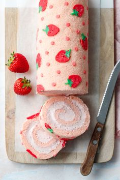 strawberry cake with frosting and sliced strawberries on cutting board