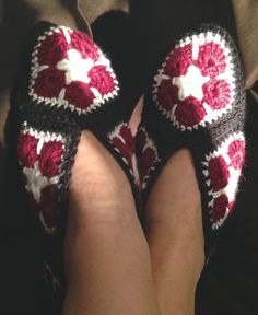 someone is wearing crocheted slippers with red and white flowers