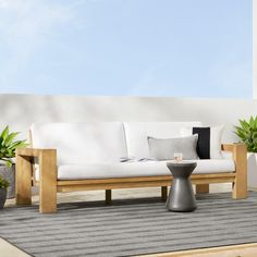 a white couch sitting on top of a wooden floor next to potted planters