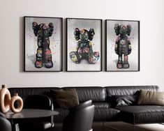 three framed art pieces hang on the wall above a couch in a living room with black leather furniture