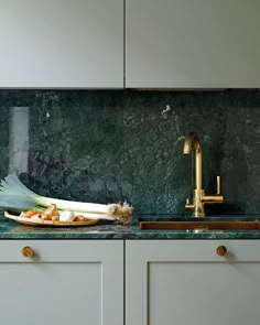 a kitchen with green marble counter tops and gold faucet