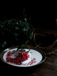 a white plate topped with food on top of a wooden table next to greenery